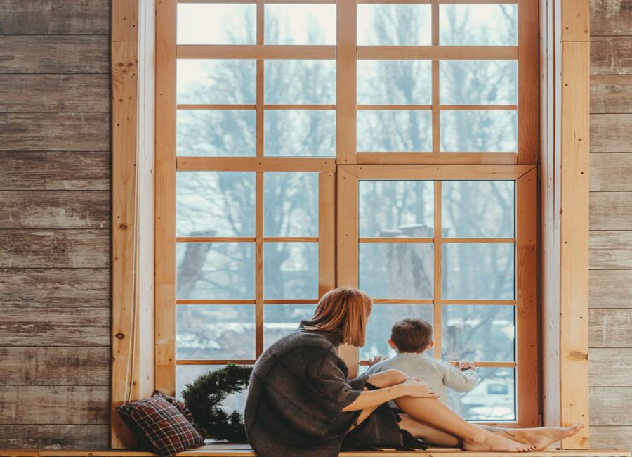 femme et enfant devant châssis en bois en hiver
